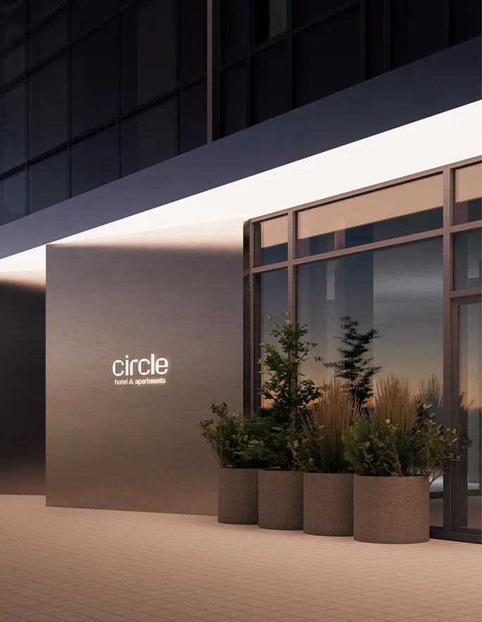 Фасад сучасної будівлі з логотипом Circle (hotel & apartments), великими прозорими вікнами, металевим каркасом, рослинами у горщиках на терасі та вечірнім освітленням.