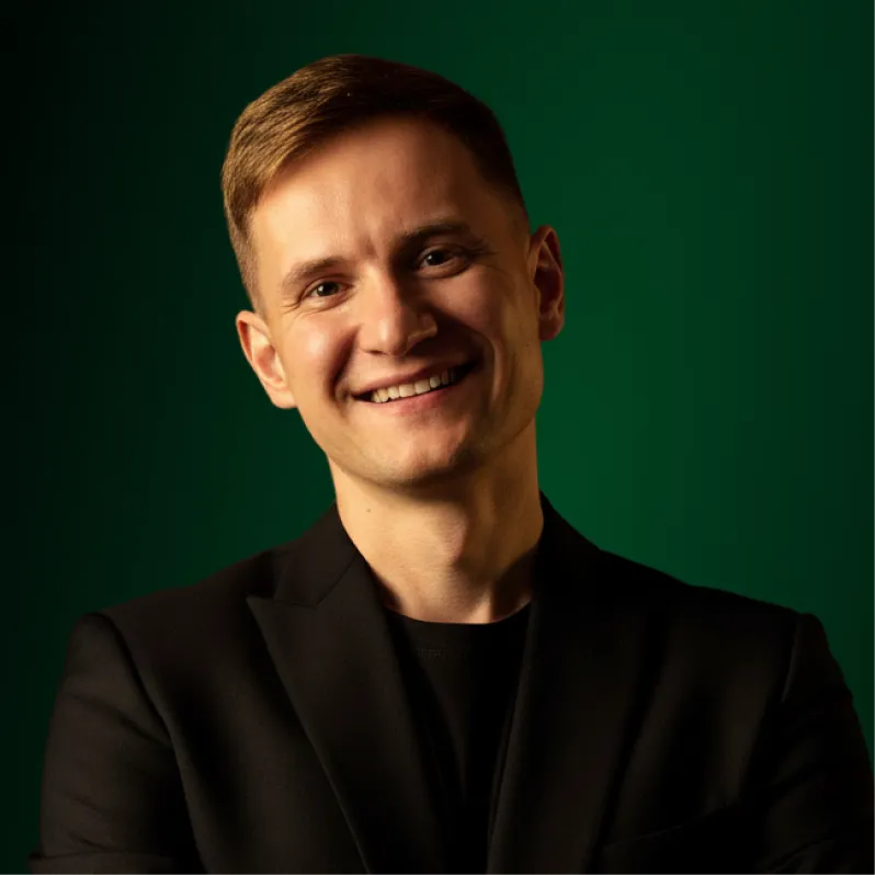 A portrait of Andriy Sambir against a green background.
