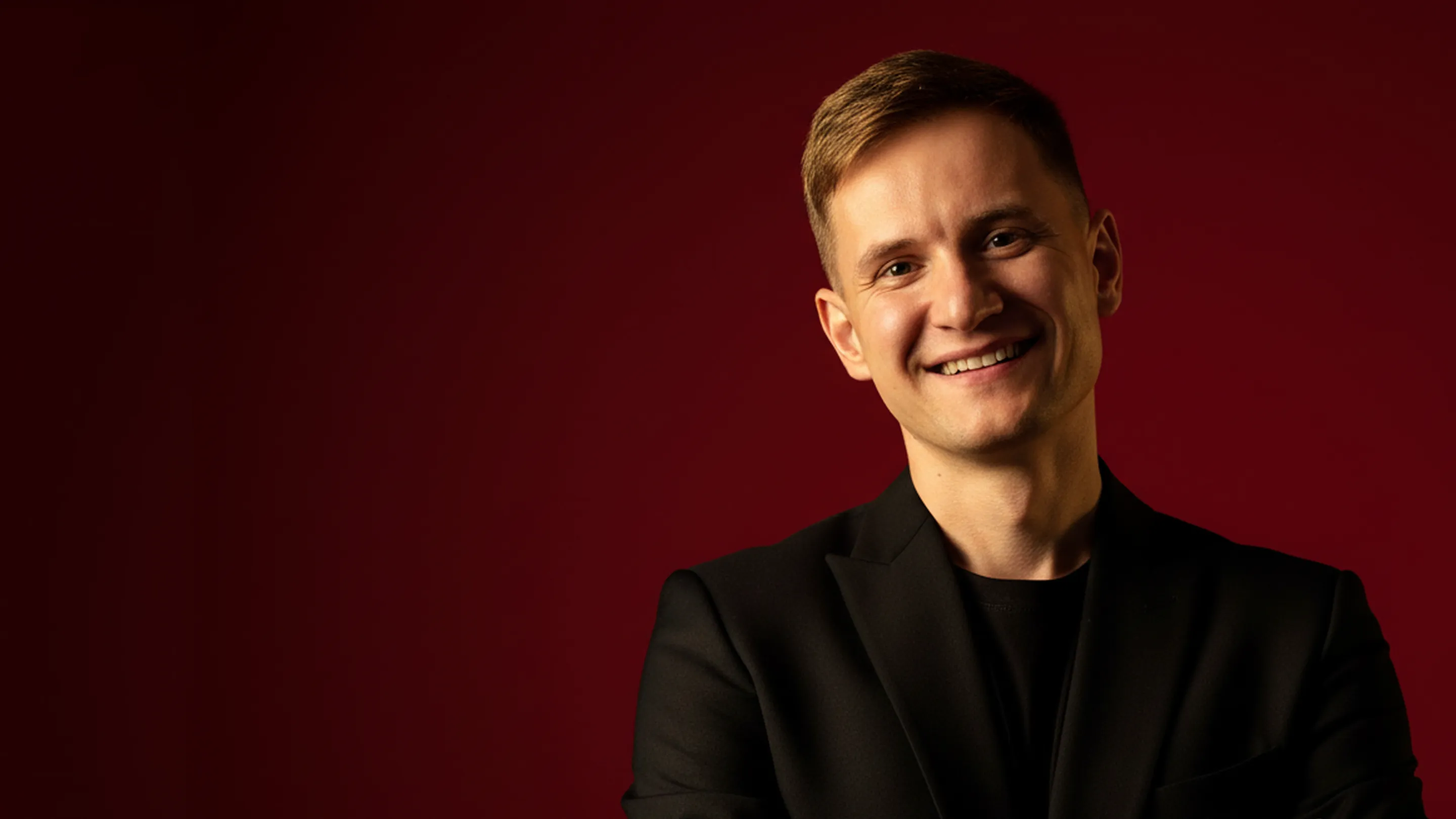 Портрет Андрія Самбора на бордовому фоні.